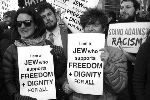 Protest image of people holding signs that read "I am a Jew and I believe in freedom and dignity for all"