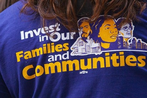 A T-shirt that reads "Invest in our families and communities"