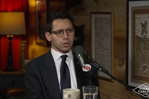 a man in a suit sitting behind a microphone