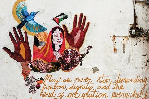 a mural of a paste up and the words "May we never stop demanding freedom dignity and the end of occupation everywhere from Palestine to Kashmir"