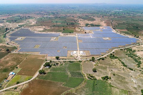 An aerial view of a solar panel field surrounded by bare fields