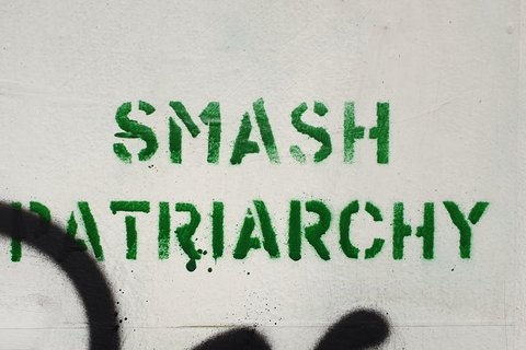 A beige wall with the words "smash patriarchy" graffitied in green on it.