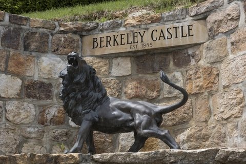 a statue of a roaring lion in front of a stone sign reading "berkeley castle"
