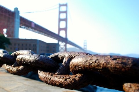 A large chain in front of a suspension bridge