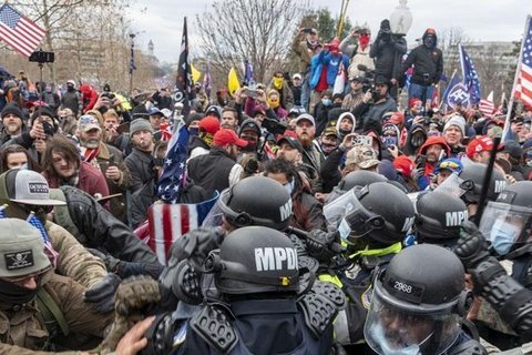 A crowd of pro-Trump insurrectionists push back against a swarm of police in SWAT gear.