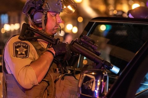 Sheriff with machine gun pointed into SUV