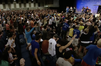 A group of people in a room with their hands raised.
