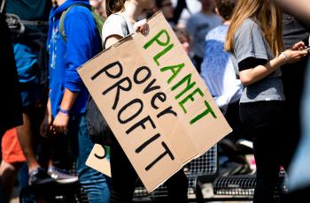A sign at a protest saying "planet over profit"