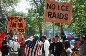 Protestors with signs saying "Immigrants are not criminals" and "No I.C.E. raids"