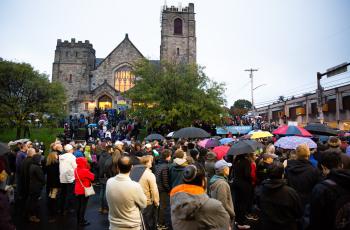 A group of people standing in front of a synagogue with umbrellas open