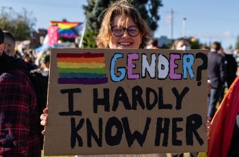 A sign at a protests saying "Gender? I hardly know her"