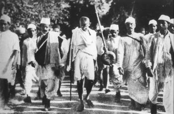 a black and white photo on people marching on the street, wearing hats and dhotis
