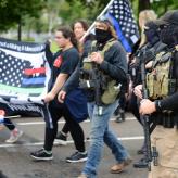 Armed militia members march next to a WWG1WGA flag, a common identifier of QAnon believers, at the United We Stand & Patriots March for America, St. Paul, Minnesota, September 12, 2020 (Credit: Fibonacci Blue/Flickr).