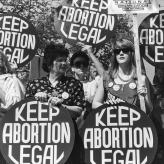 White women protesting, holding circular signs that say "Keep Abortion Legal"