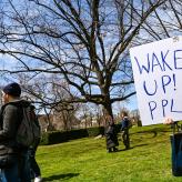 A woman holding a sign saying "Wake up! Ppl"