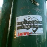 A flyer on a pillar that reads: "This is a fascist free zone. Antifa"