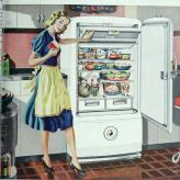 A white woman in a blue dress and a yellow apron, standing in front of an open fridge full of food.
