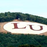 The letters LU in red on a green mountain