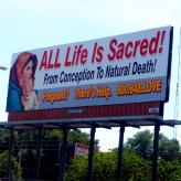 a billboard that says "All life is Sacred! From conception to natural death! Pregnant? There's Help. 800.748.LOVE"