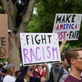 A person holding a sign saying "Fight Racism"