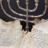 Old scrolls of the Bible and Menorah lie on a black background.