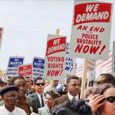 People at a protest holding a sign that says "We Demand Voting rights now!" "We demand An end to police brutality now"