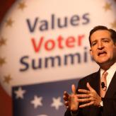 A man in the middle of a speech in a suit with "Values Voter Summit" in the background.