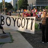 Two people holding a sign that says "Boycott" at a protest