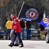 Two people in red hoodies carrying a QAnon flag