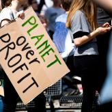 A sign at a protest saying "planet over profit"