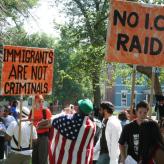 Protestors with signs saying "Immigrants are not criminals" and "No I.C.E. raids"