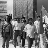 a black and white image of men holding flags walking.