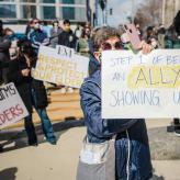 a person holding a sign that says "step 1 of being an ally is showing up."