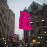 Woman holds a pink sign that reads "resist trump"