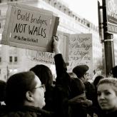 A protestor holding a sign that says "build bridges not walls"
