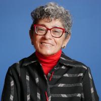 A woman with grey hair wearing red glasses.
