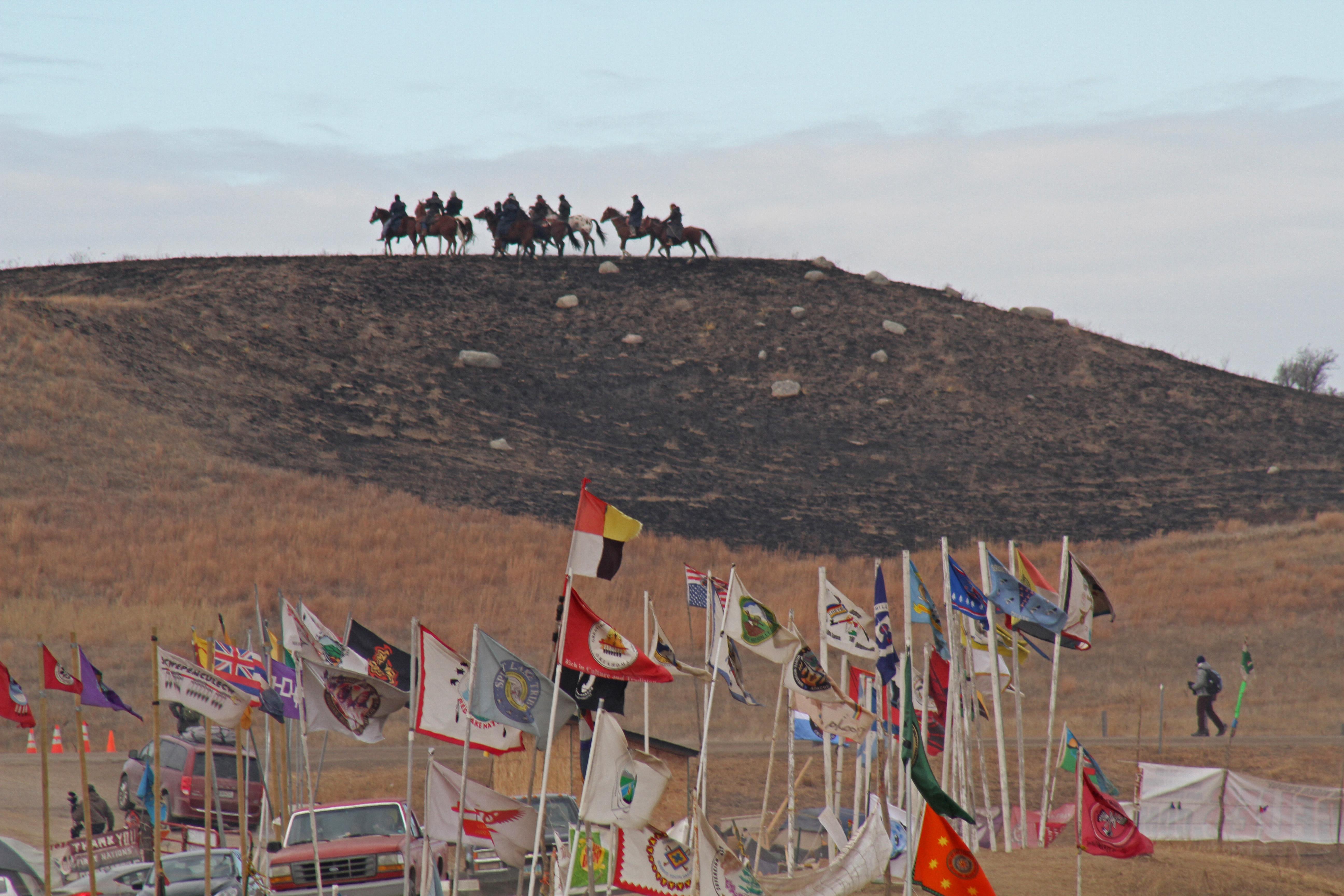 Riders on horseback overlook Oceti Sakowin Camp occupied by Standing Rock protesters.