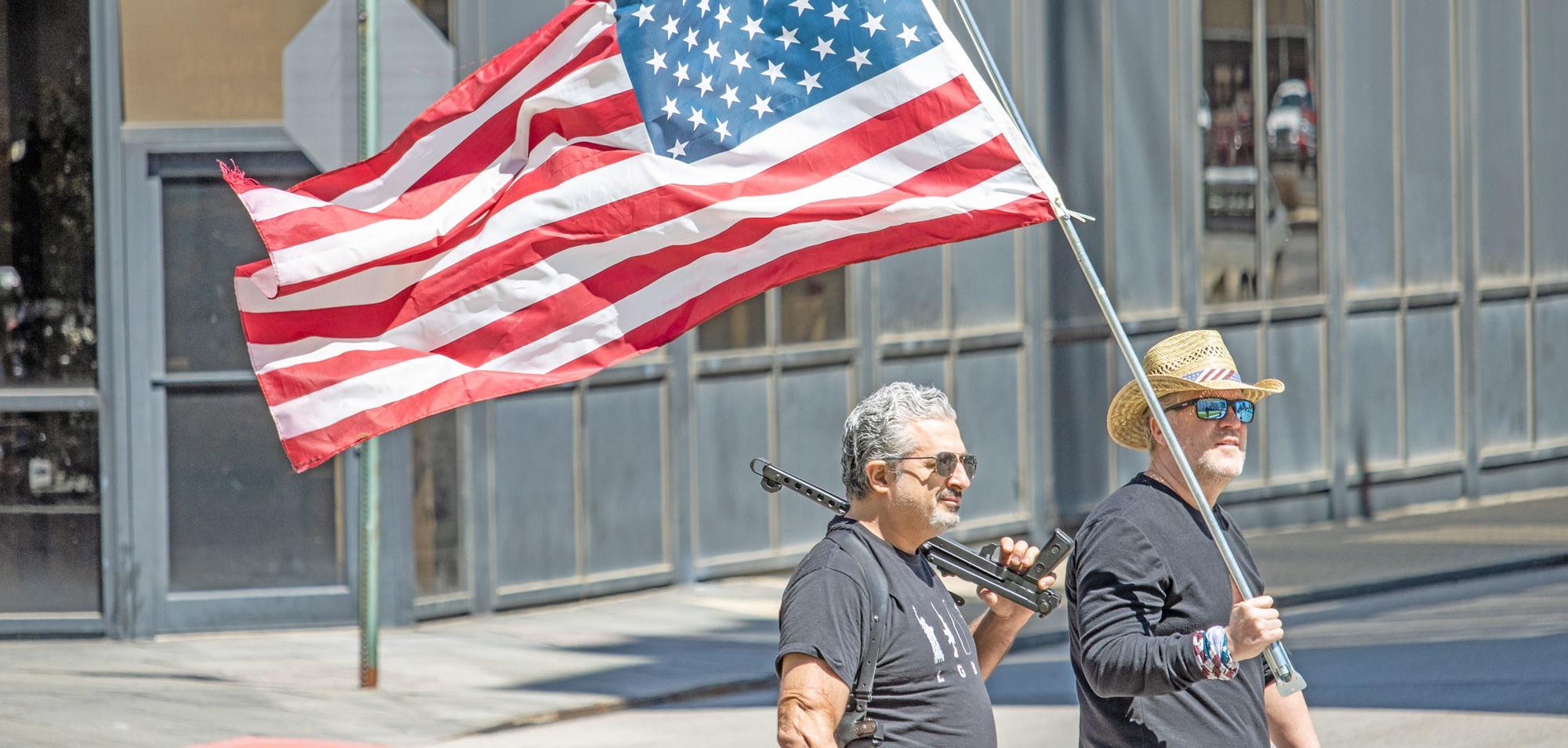 Coronavirus lockdown protestors hold American flag and gun, April 21, 2020 (Credit: Becker1999/flickr)