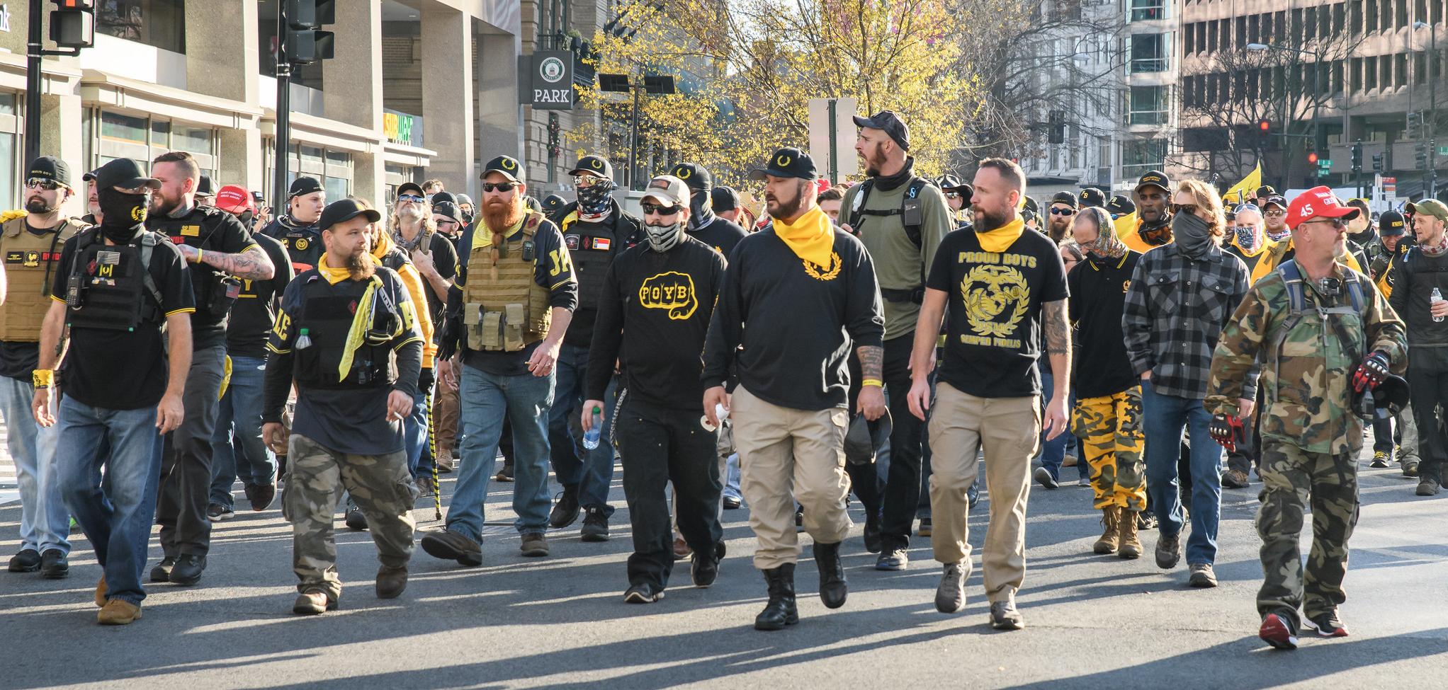 A group of men, in Proud Boys gear walking on a street.