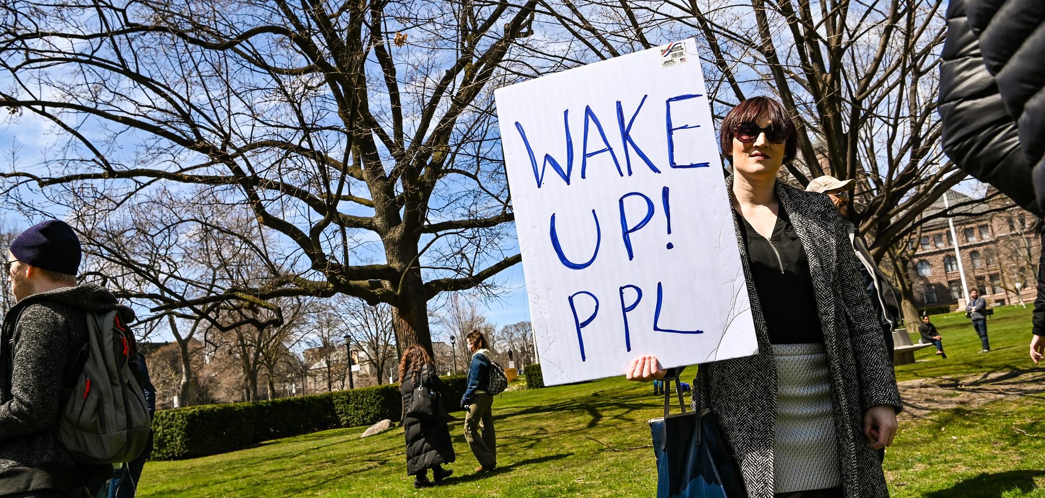 A woman holding a sign saying "Wake up! Ppl"