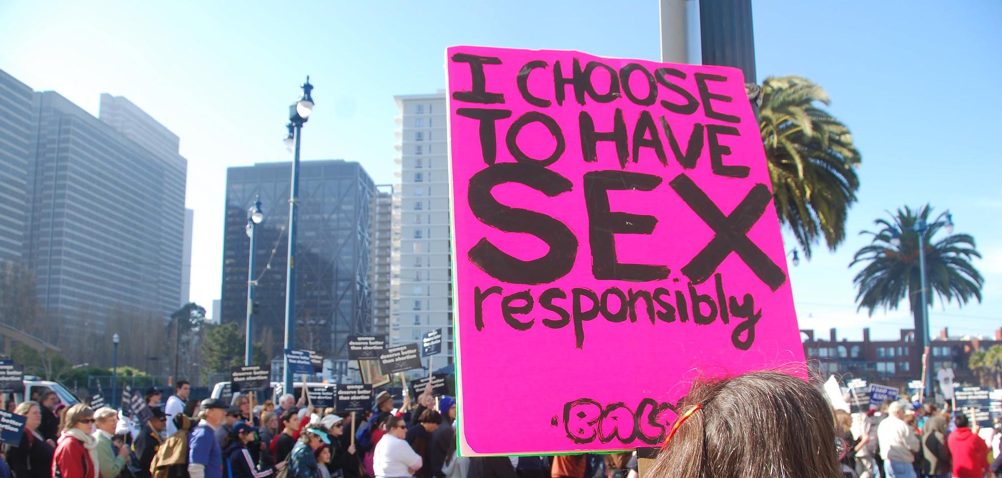 A person holding a sign that reads "I choose to have sex responsibly"