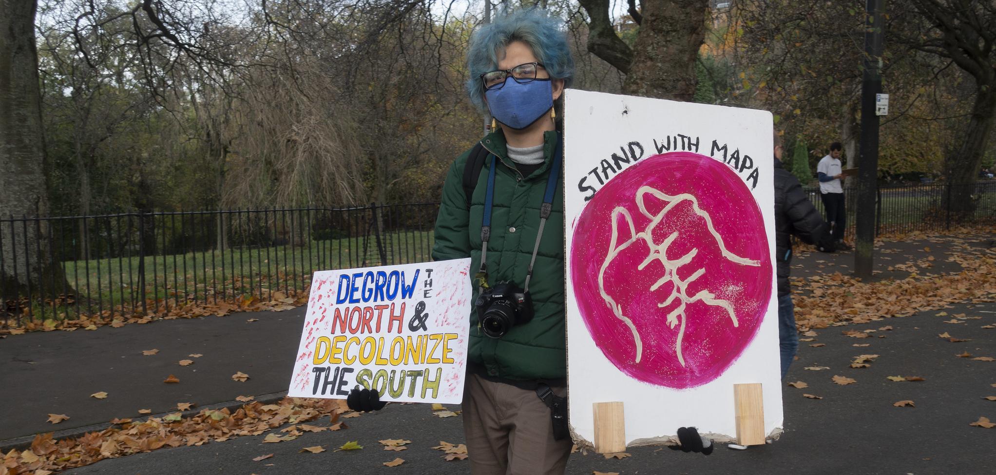 A person at a protest holding a sign that says DeGrow the North and Decolonize the south