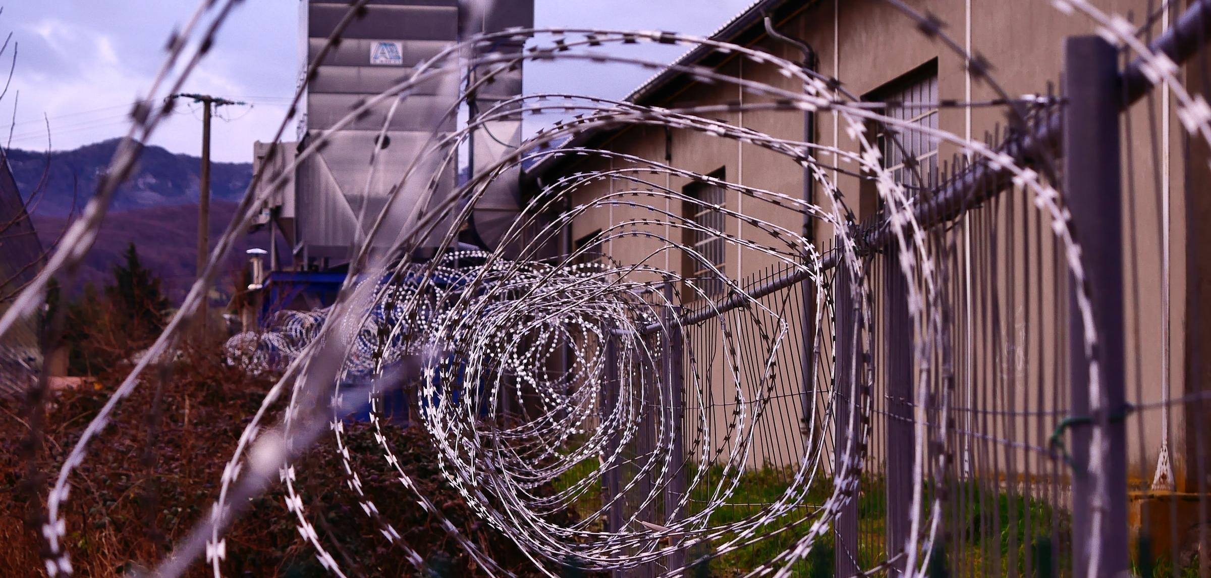 Barbed wire in a spiral form outside a brown building.