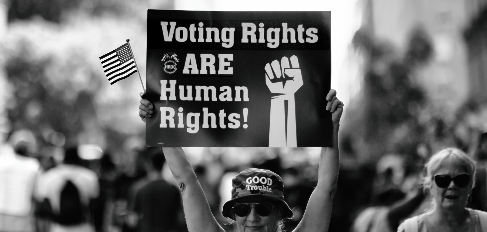 A person holding a banner saying "voting right are human rights!"