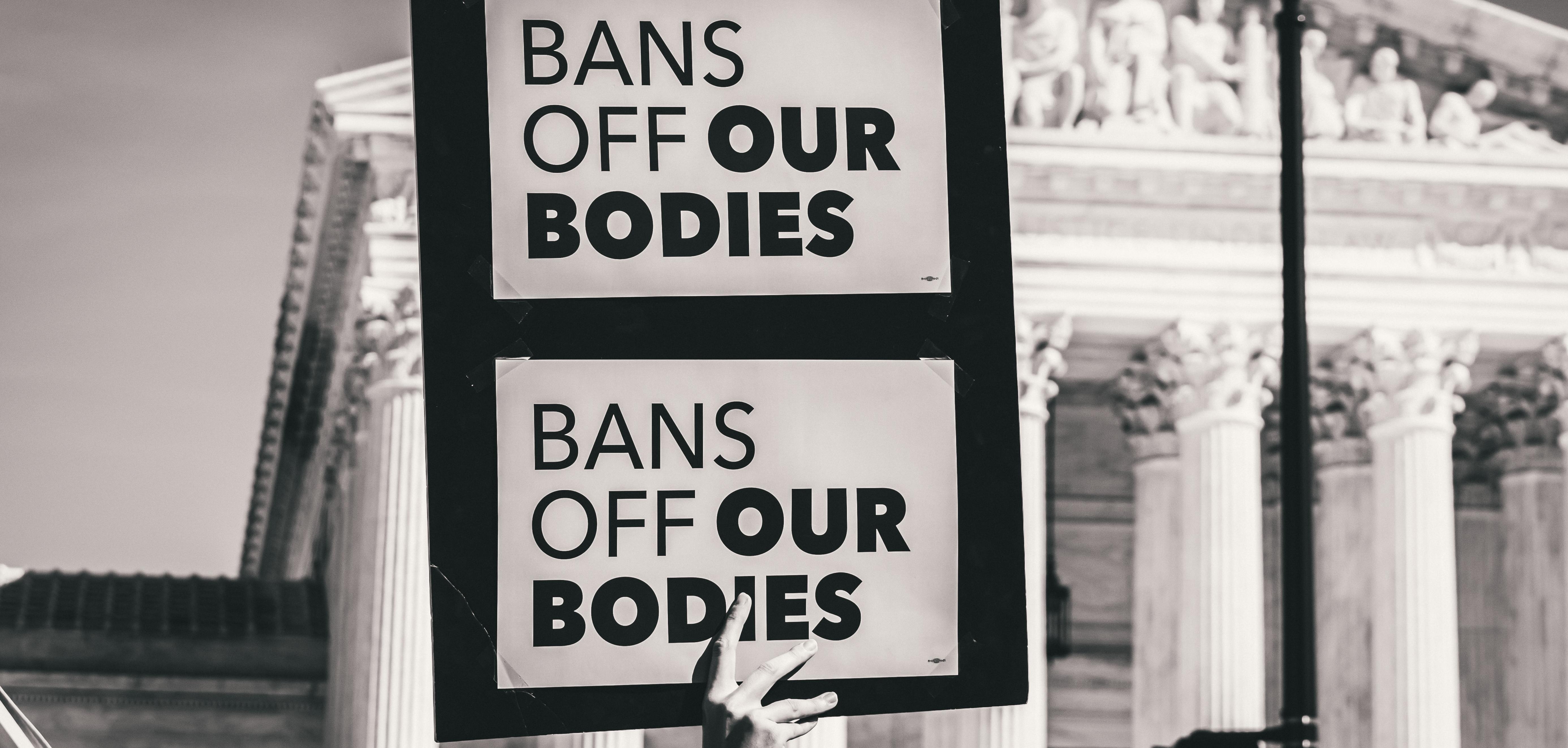 A protestor holding a paper that says "Bans of our bodies"