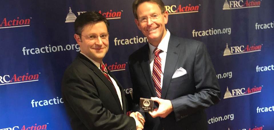 Two men in suits and glasses standing in front of a background saying "FRCAction"