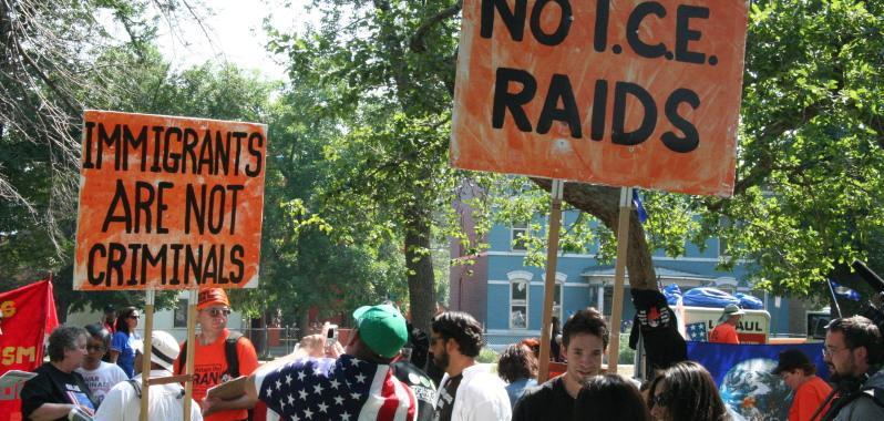 Protestors with signs saying "Immigrants are not criminals" and "No I.C.E. raids"