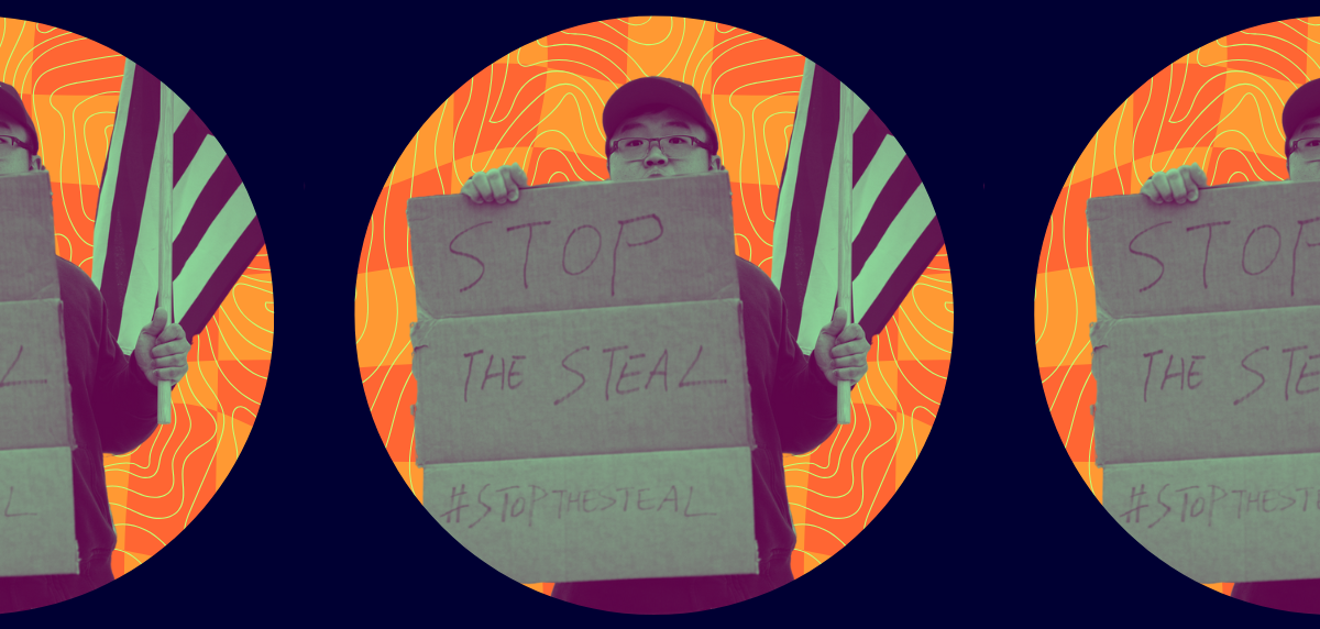 A protestor holds an American flag and a sign reading "Stop the Steal"