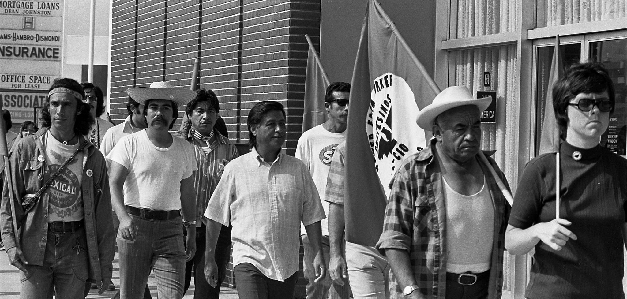 a black and white image of men holding flags walking.