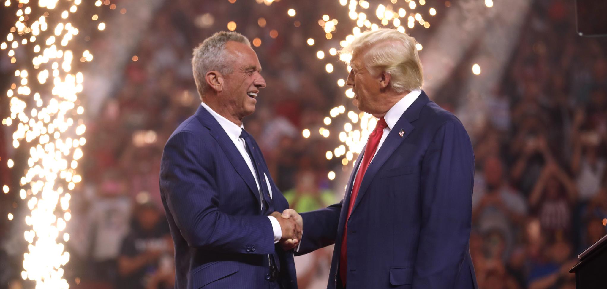 Two men shaking hands with fireworks behind them.